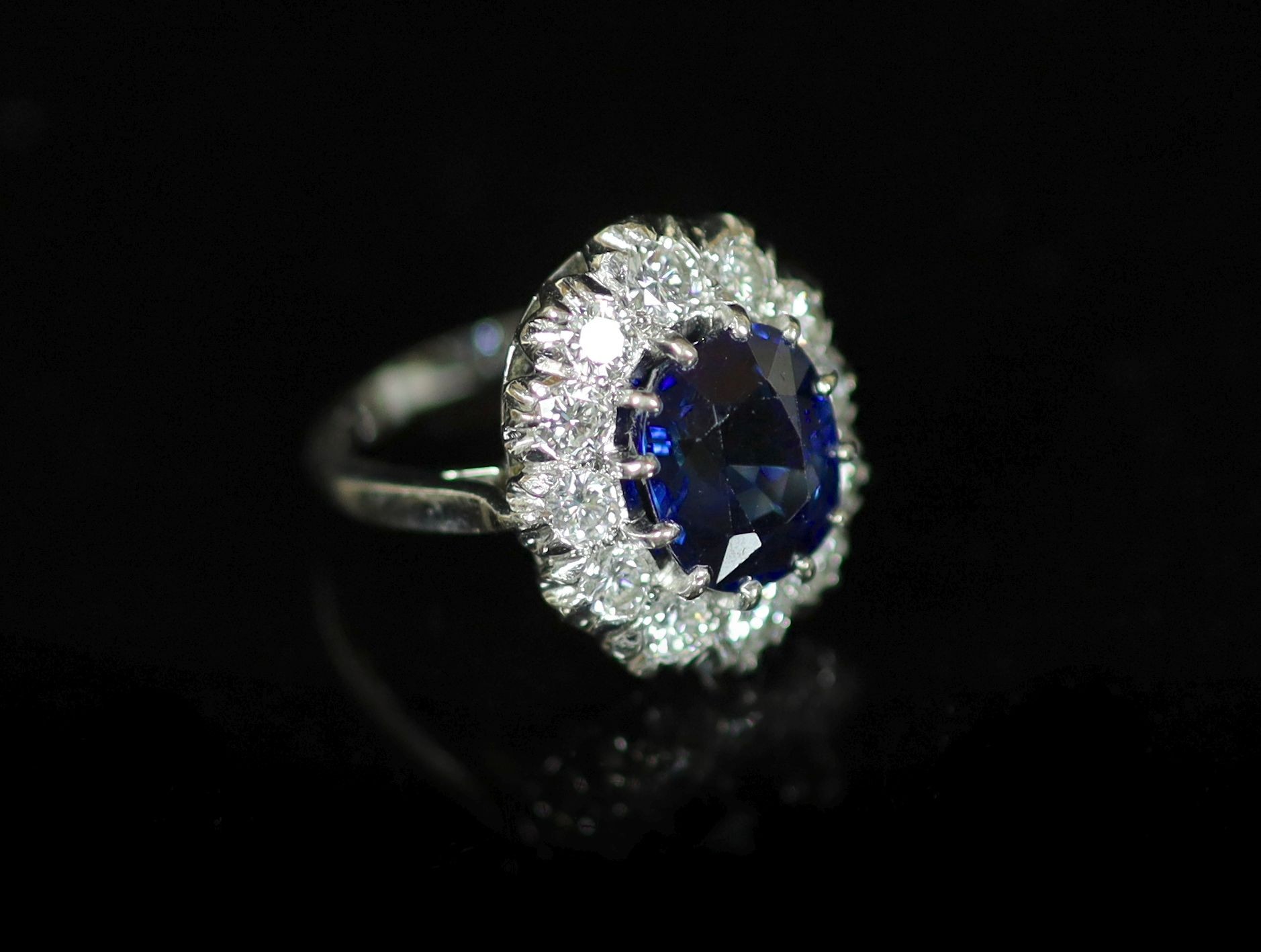 A modern 18ct white gold, sapphire and diamond set oval cluster ring, by Garrard & Co